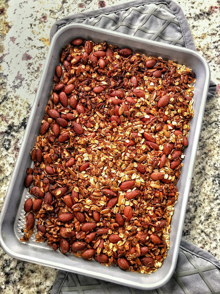 healthy homemade granola on a sheet pan with oven mitts