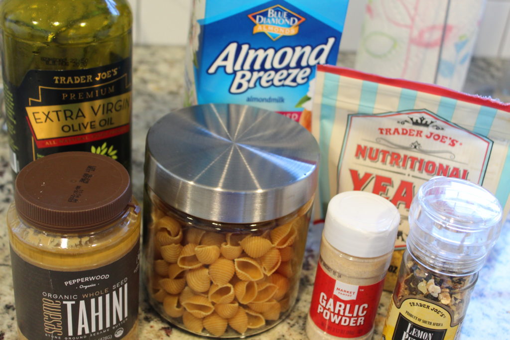 ingredients for vegan alfredo pasta. olive oil, banza shells, tahini, almond milk, nutritional yeast, garlic powder, lemon pepper